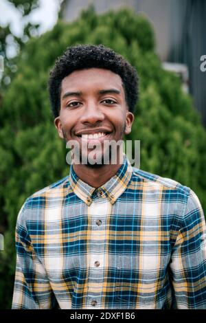 Lächelnder junger afrikanischer Bauer mit lockigen Haaren lächelt im Garten Zentrieren Stockfoto