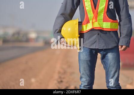 Nahaufnahme Engineering Holding Yellow Helm Hard Hut Sicherheit und Straßenbau Hintergrund Stockfoto