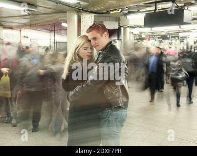 Junges Paar umarmt sich gegenseitig, während sie an der U-Bahn-Station stehen Während der Hauptverkehrszeit Stockfoto