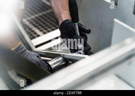 Hände eines männlichen Technikers, der die Maschinenmutter mit einem Schraubenschlüssel befestigt Branche Stockfoto