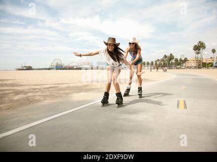 Glückliche Freunde, die Spaß beim Inline-Skaten auf der Straße durch Strand Stockfoto