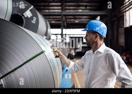 Man scannt Barcode auf Stahlrollen, während man in der Industrie steht Stockfoto