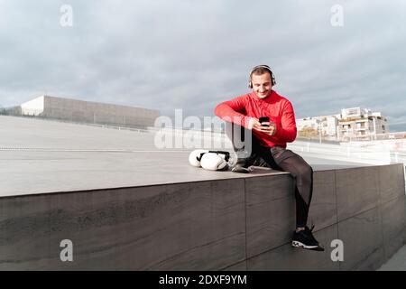 Sportler mit Kopfhörern mit Mobiltelefon im Freien Stockfoto