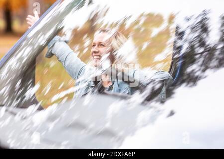 Fröhliche Frau durch die Windschutzscheibe des Wohnhauses gesehen Stockfoto