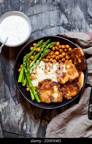 Dipping Sauce und Schüssel Reis mit Kichererbsen, Spargelstielen und gebratenem Halloumi-Käse Stockfoto