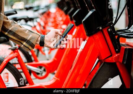Mans Hand hält Smartphone, um Fahrrad zu mieten Stockfoto