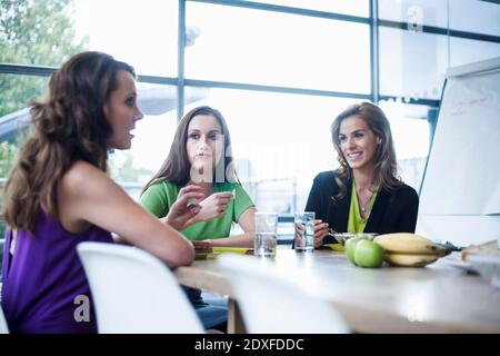 Weibliche Geschäftskollegen beim Mittagessen, während sie in der Cafeteria diskutieren Büro Stockfoto