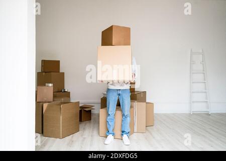 Junger Mann, der Stapel von Kisten trägt, während er neu steht Wohnung Stockfoto