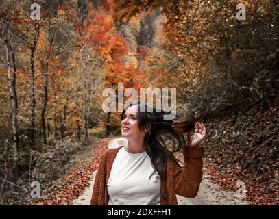 Ein flacher Fokus Nahaufnahme einer Frau, die auf der geht Straße mit gefallenen Blättern während der Herbstsaison Stockfoto