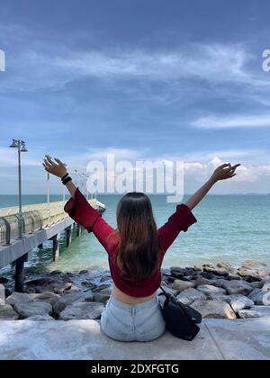 Asiatische Frauen stehen vor dem wunderschönen Pier des Eastern and Oriental Hotel unter blauem Himmel. Das berüchtigte Hotel in Penang, Malaysia. Stockfoto