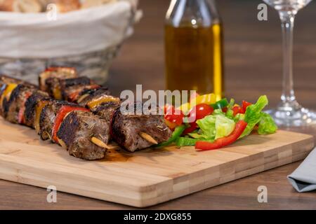 Verlockende Rinderspieße neben sortierten geschnittenen Gemüse auf einem hölzernen Schneidebrett auf einem unfokussierten Hintergrund. Selektiver Fokus und Nahaufnahme. Stockfoto