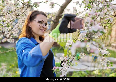 Glückliche Frau im blühenden Garten macht Selfie-Foto auf dem Smartphone Stockfoto