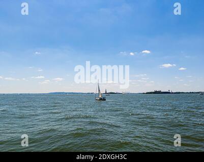 Segelboote im Hudson River mit Liberty Island im Hintergrund Warmer Sommertag Stockfoto