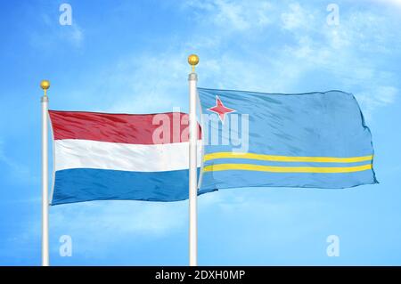 Niederlande und Aruba zwei Flaggen auf Fahnenmasten und blauer Himmel Stockfoto