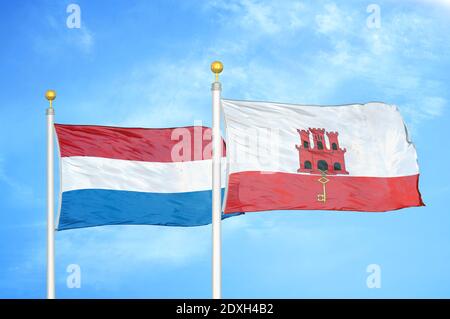 Niederlande und Gibraltar zwei Flaggen auf Fahnenmasten und blauer Himmel Stockfoto