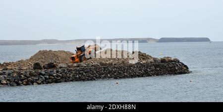 Bulldozer bei der Arbeit bewegen Stein Meer im Hintergrund. Gebäude Steg. Stockfoto