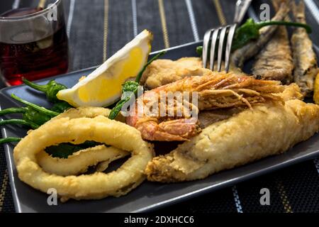 Nahaufnahme von Gerichten mit goldgebratenem Fisch und Wein Stockfoto