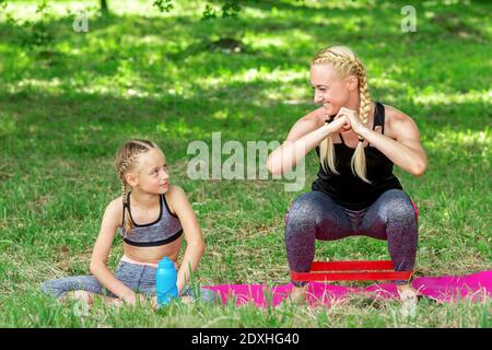 Mutter und Tochter machen Sportübungen auf der Matte in Der Park im Freien Stockfoto