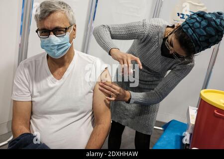 Jerusalem, Israel. Dezember 2020. Krankenschwestern verabreichen COVID-19-Impfstoffe an ältere Menschen ab 60 Jahren im Pais Arena Sports Complex in Jerusalem, der in ein Coronavirus-Impfzentrum umgewandelt wurde. Mehr als 100,000 israelische Bürger haben bereits die erste von zwei Dosen des Pfizer BioNTech-Impfstoffs in einer Massenimpfkampagne erhalten, während die Regierung eine dritte landesweite Sperre ab 27. Dezember 2020 plant, angesichts der anhaltenden Infektion. Kredit: Nir Alon/Alamy Live Nachrichten Stockfoto