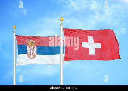 Serbien und die Schweiz zwei Flaggen auf Fahnenmasten und blauer Himmel Stockfoto