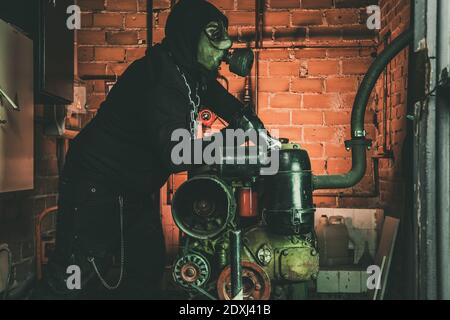 Mann mit Gasmaske und Hammer im Maschinenraum. Nukleare, biologische und chemische Gefahrenkonzept. Stockfoto