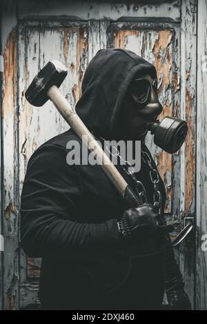 Mann mit Gasmaske und Hammer im Maschinenraum. Nukleare, biologische und chemische Gefahrenkonzept. Stockfoto