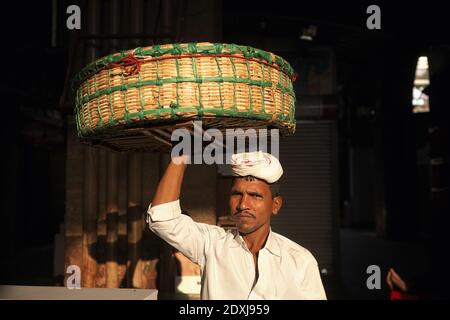 Porträt eines Portiers auf dem Crawford Market (Mahatma Jyotiba Phule Market), einem großen Obstmarkt in Mumbai, Indien, der seinen Korb über den Kopf balanciert Stockfoto