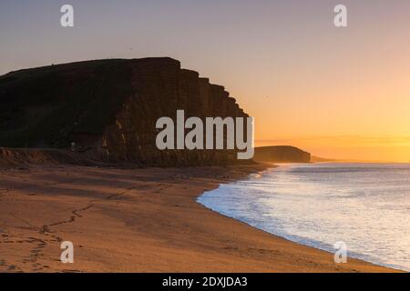 West Bay, Dorset, Großbritannien. Dezember 2020. Wetter in Großbritannien. Sonnenaufgang am Strand von West Bay in Dorset an einem kalten, klaren, sonnigen Morgen am Heiligabend. Bild: Graham Hunt/Alamy Live News Stockfoto