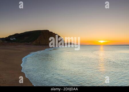 West Bay, Dorset, Großbritannien. Dezember 2020. Wetter in Großbritannien. Sonnenaufgang am Strand von West Bay in Dorset an einem kalten, klaren, sonnigen Morgen am Heiligabend. Bild: Graham Hunt/Alamy Live News Stockfoto