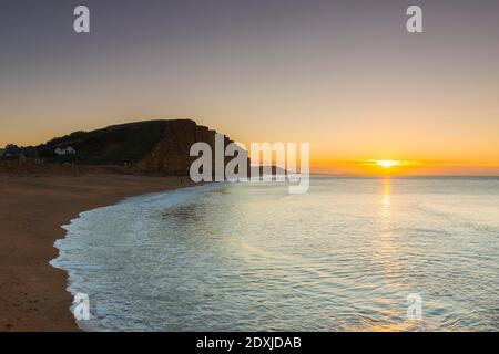 West Bay, Dorset, Großbritannien. Dezember 2020. Wetter in Großbritannien. Sonnenaufgang am Strand von West Bay in Dorset an einem kalten, klaren, sonnigen Morgen am Heiligabend. Bild: Graham Hunt/Alamy Live News Stockfoto