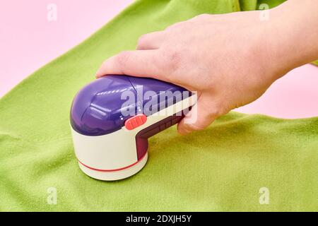 Ein Woman mit Fabric Shaver entfernt Stoffpillen von Kleidungsstücken. Nahaufnahme, selektiver Fokus Stockfoto
