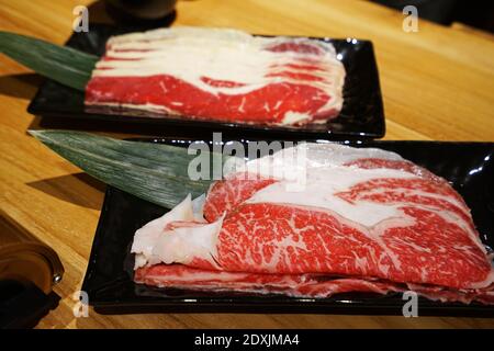 Frisch und roh geschnittenes japanisches Wagyu-Rind auf schwarz dekoriert Keramikplatte Stockfoto