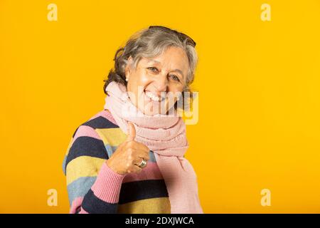 Ältere Frau in legerer Kleidung zeigt OK Zeichen gegen ein Gelber Hintergrund Stockfoto