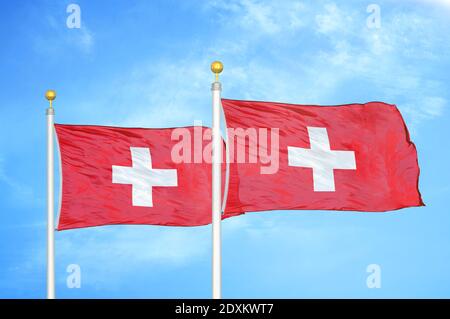 Schweiz zwei Flaggen auf Fahnenmasten und blauer Himmel Stockfoto