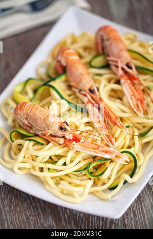 Handgemachte Tagliatelle mit Garnelen und Zucchini auf einem Teller. Stockfoto