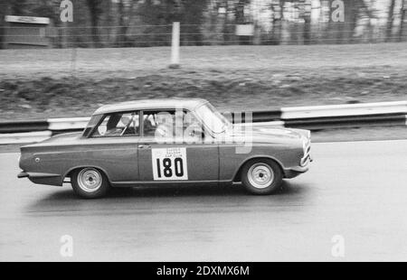 Vintage Schwarz-Weiß-Foto aus dem Jahr 1983 zeigt Lotus Cortina UBM 1, Rennnummer 180, Rennen auf der Brands Hatch Rennstrecke in England. Stockfoto