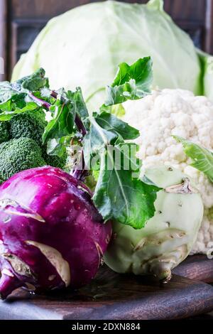 Verschiedene Arten von Kohl wie Weißkohl, Blumenkohl, Brokkoli, Kohlrabi auf dunklem Tisch, Herbsternte, selektiver Fokus Stockfoto