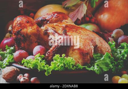 Festlich gebackenes Hähnchen mit Herbstbeeren, Früchten, Nüssen und Gemüse im rustikalen Stil des alten Holzhintergrunds, selektiver Fokus und getönter ima Stockfoto