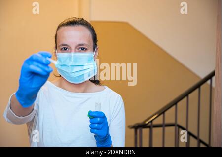 Medizinische Krankenschwester an der Wohnungstür mit einem Tupfer für covid 19 allgemeine Bevölkerung Tests an der Hausadresse. Stockfoto