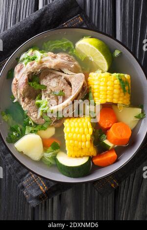 Caldo de Res ist eine mexikanische Rindsuppe mit viel Gemüse wie Kürbis, Mais, Karotten, Kohl und Kartoffeln in der Nähe auf dem Teller auf dem Tisch. Version Stockfoto