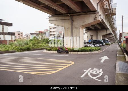 Hsinchu / Taiwan - 20. März 2020: Person, die Motorroller unter Zugbrücke in einer leeren Straße fährt Stockfoto
