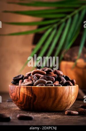 Ungeschälte Kakaobohne auf rustikalem Holzhintergrund, Nahaufnahme. Speicherplatz kopieren Stockfoto
