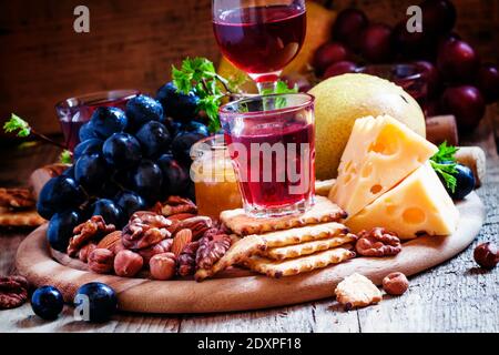 Rosenwein und Holzgericht mit verschiedenen Snacks, Vintage-Hintergrund, selektiver Fokus Stockfoto