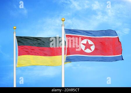 Deutschland und Nordkorea zwei Flaggen auf Fahnenmasten und blau wolkiger Himmel Stockfoto