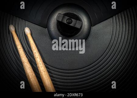 Extreme Nahaufnahme von zwei verwendeten Holzschlagstöcken auf einem schwarzen Becken eines elektronischen Schlagzeug, Percussion Instrument. Stockfoto