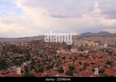 Panoramablick auf ungeplante Urbanisierung und orange Ziegeldach Gebäude aus Ankara, der Hauptstadt der Türkei und ein Regenbogen Im Hintergrund Stockfoto