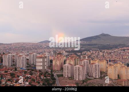 Panoramablick auf ungeplante Urbanisierung und orange Ziegeldach Gebäude aus Ankara, der Hauptstadt der Türkei und ein Regenbogen Im Hintergrund Stockfoto