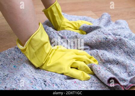 Mädchen in Gummihandschuhen wäscht den Boden zu Hause mit einem Lappen. Konzept der Hausarbeit und Housekeeping Stockfoto