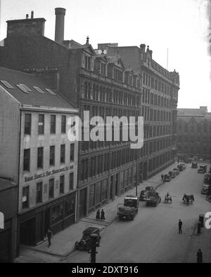 1930s, historisch, Glasgow, Schottland, Großbritannien. Blick von oben auf die Aktivität in einer Straße im Zentrum der Stadt. Links auf dem Bild ist das Werkgebäude von Sisson Brothers & Co, einem Paiint-Hersteller, der 1803 in Bankside, Hull, England, als Sisson Paints gegründet wurde und 1827 zu Sisson Brothers wurde. Am späten Ende des 19th. Jahrhunderts eröffneten sie Depots in anderen Teilen Großbritanniens, einschließlich Glasgow. 1956 wurde das Unternehmen von Reckitt & Colman aus Hull, dem berühmten Senfunternehmen, gekauft. in1969 Sisson-Farben wurden nicht mehr hergestellt und das Unternehmen wurde eingestellt und der Fabrikkomplex in Hull geschlossen. Stockfoto