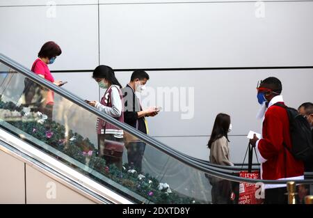 Hongkong, China. Dezember 2020. Menschen mit Gesichtsmasken nehmen eine Rolltreppe in Hongkong, Südchina, 24. Dezember 2020. Das Zentrum für Gesundheitsschutz in Hongkong (CHP) meldete am Donnerstag 71 weitere bestätigte Fälle von COVID-19, insgesamt 8,424. Quelle: Wu Xiaochu/Xinhua/Alamy Live News Stockfoto